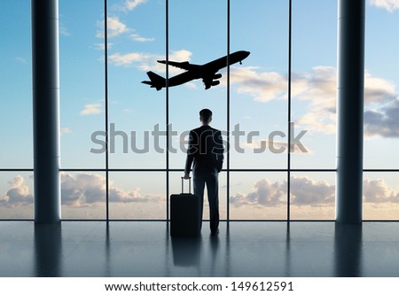 man in airport with luggage and looking in airplane