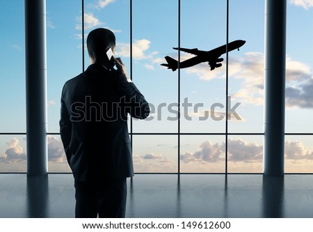 Businessman With Phone And Airplane In Sky