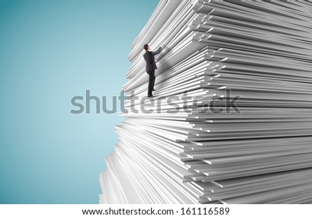 young man climbing up a huge big stack of paper