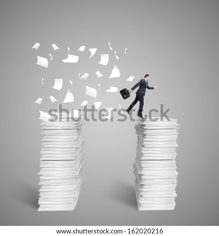 man jumping from top to top of a mountain of papers