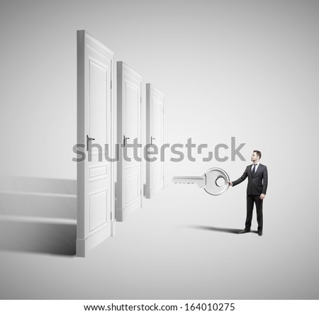 businessman holding big key with closed doors