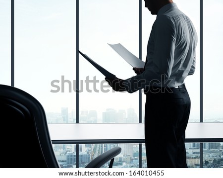 businessman with paper in office against background of city