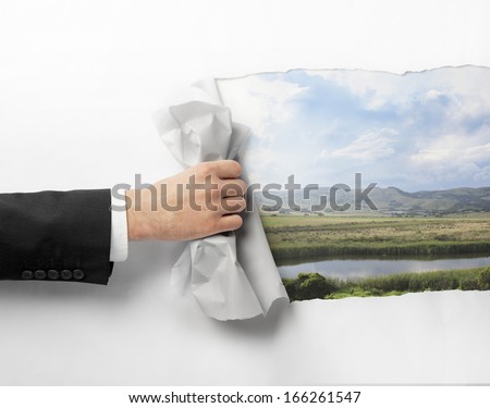 hand tears white page to nature