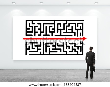 businessman looking at labyrinth on white poster on wall