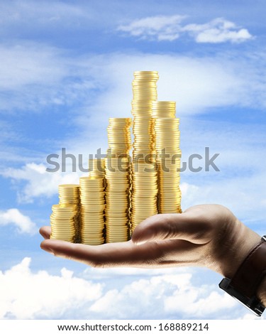 hand holding gold coins city on sky background