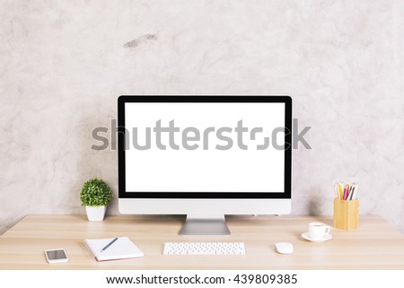 Creative hipster desktop with blank white computer screen, coffee cup, smart phone and other items on concrete background. Mock up