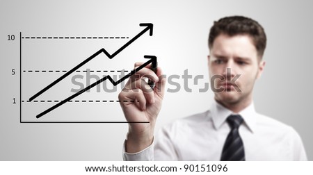 Young business man drawing a graph on a glass window in an office - focus is on graph. Businessman drawing a rising arrow, representing business growth. Man coming up with an idea on a glass screen