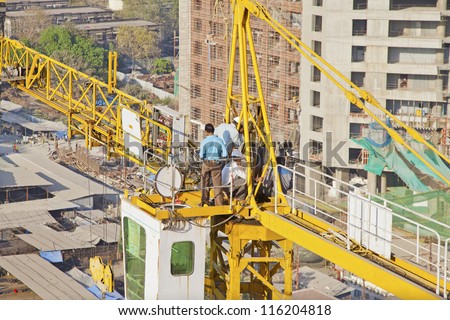 MUMBAI, INDIA - MARCH 12 :Engineers repairing high rise crane at a building and builders development working without a safety harness on March 12, 2011 in Bombay, India