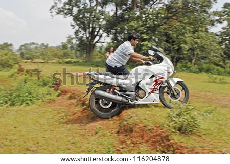 PACHMARHI, MADHYA PRADESH, INDIA - SEPTEMBER 30:Motorcyclist pushes his bike over a garden ridge at parkland during Bike Nomads bikers meet September 30 2012 Pachmarhi Madhya Pradesh India.