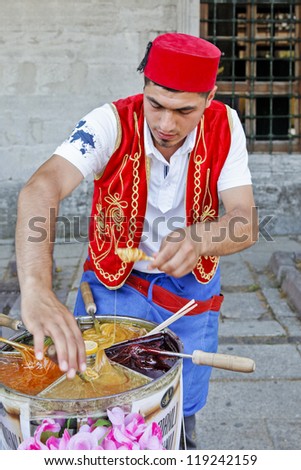 ISTANBUL, TURKEY - JUNE, 25: Fast hands of a street stall vendor preparing a multi colored caramel on a stick in on June 25, 2001 in Istanbul, Turkey. A delicacy served near tourist attractions.