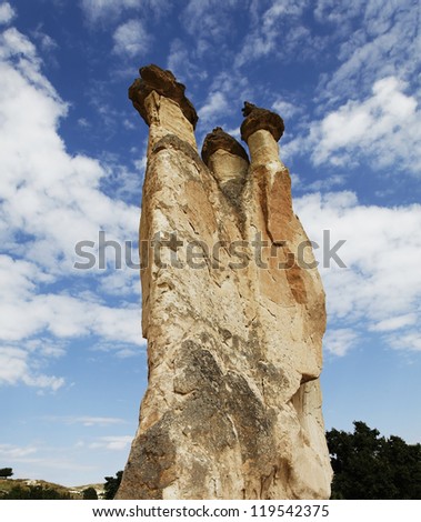 striking vertical shot of a limestone fairy chimney formed by weathering evolution against a strong sky and clouds background. Shot location was Anatolia / Cappadocia Turkey