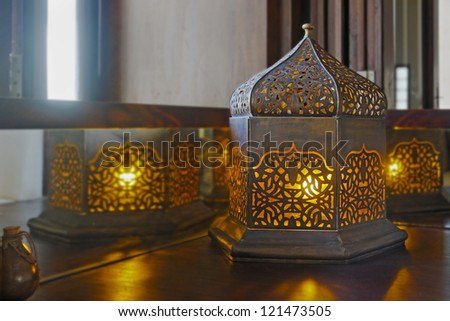 Generic oriental table lamp set on corner table with yellow bulbs switched on giving amber glow. Location of shot, India