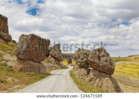 Rural countryside of Turkey, Volcanic activity left boulders perched precariously on either side of the dirt track graveled road. No signage that warns of avalanche. Shot location was Cappadocia