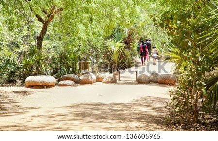 AUROVILLE, TAMIL NADU, INDIA  - APRIL, 12: An asian family taking an afternoon stroll in lush green and landscaped gardens on April 12, 2013 in Auroville, Tamil Nadu, India
