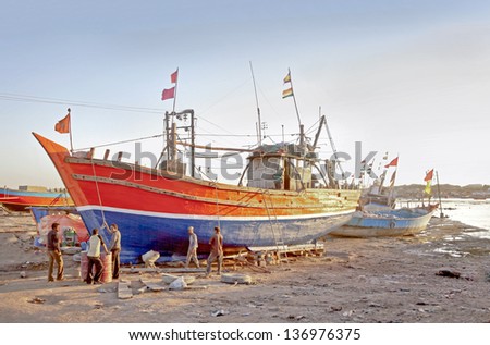 GUJARAT, INDIA - FEBRUARY 27, 2013: Boatyard on estuary of Okha where repair crew are in discussion on the strategy of a repair job on boat grounded on the bank on February 27, 2013 in Gujarat, India