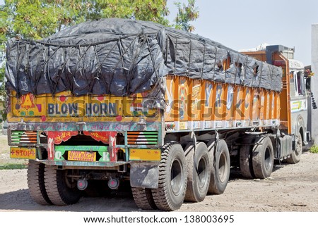 GUJARAT, INDIA - FEBRUARY 28, 2013: Colorful Indian heavy goods vehicle at  Dhabha (Indian truck stop) in the mid day sun while the driver and crew take a rest on February 28, 2013 in Gujarat, India