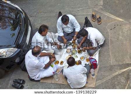 BOMBAY, INDIA - MARCH 29, 2013: Overhead shot of Indian chauffeurs having lunch in a public car park near their vehicles on the ground as if picnicking on March 29, 2013 in Bombay India