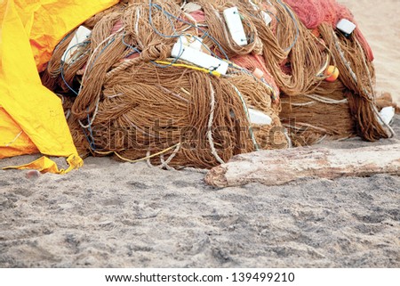 Generic horizontal color capture of a fish farming nets wrapped and stored overnight under a yellow tarpaulin on the sands at  Manaputta Beach, Pondicherry, Tamil Nadu, India