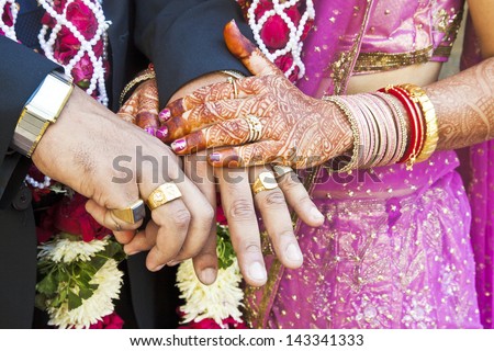 Horizontal color capture taken at a hindu wedding in Surat India. Photo session after the ceremony of the happy hand holding couple displaying their rings of matrimony and the bride lays her claim