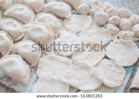 An image of raw dumplings and pieces of dumplings on the board