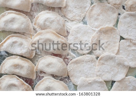An image of raw dumplings and pieces of dumplings on the board