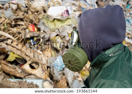 Man in a gas mask looking at garbage