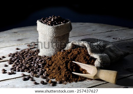 Jute Bags Filled with Ground Coffee and Coffee Beans on an Old Rustic Wooden Table , Black Background