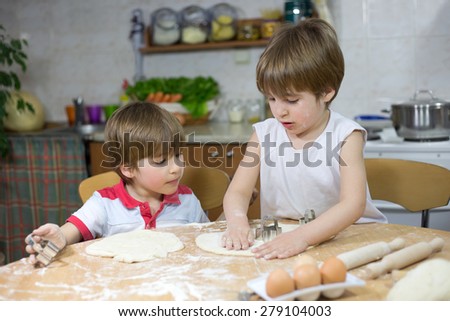 Cute Little Boy Showing His Twin Brother How to Flatten Dough at the Kitchen Table at Home