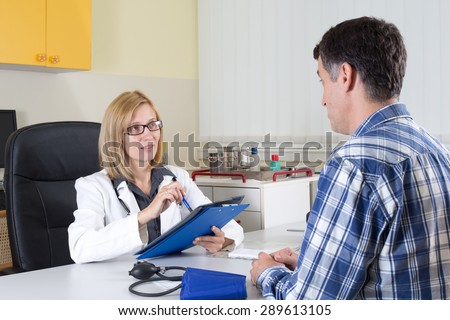 Female Doctor and Middle Aged Patient Talking in Consulting Room