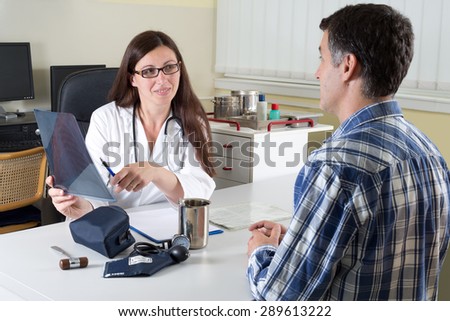 Female Doctor and Middle Aged Patient Discussing Lung X-ray Results in Consulting Room