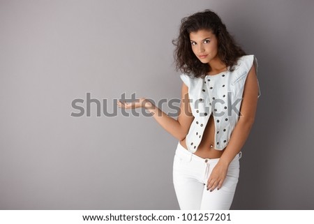 Pretty girl posing over gray background, looking at camera.