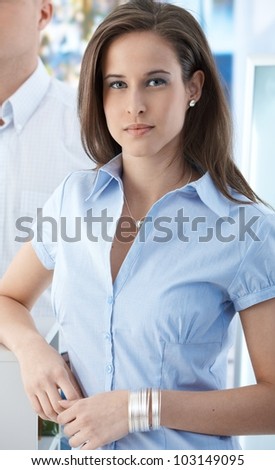 Portrait of attractive office girl standing at work, smiling at camera.