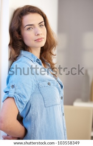 Attractive young woman standing at wall, looking away, daydreaming.