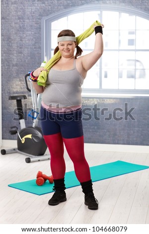 Plump woman at the gym in sportswear, smiling.