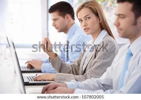 Young, attractive businesswoman sitting at meeting room, having business training.