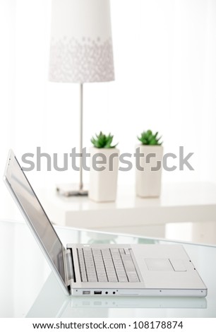 Laptop computer on white table in bright room.