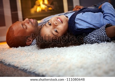 Little ethnic girl and father lying on floor at home, father sleeping.