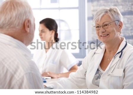 Senior doctor consulting with old man at her office.