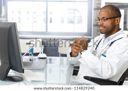 Troubled doctor sitting at desk, worried, thinking hard.