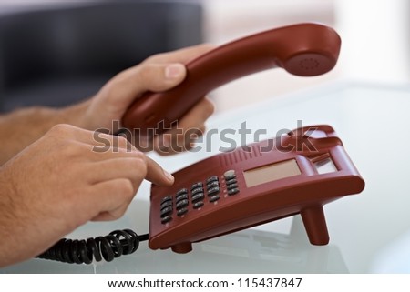 Closeup portrait of male hand dial on red landline phone.