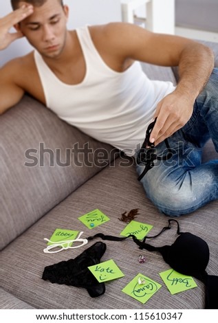 Hot young guy matching girls names on post-it notes with female jewelry accessories and underwear.