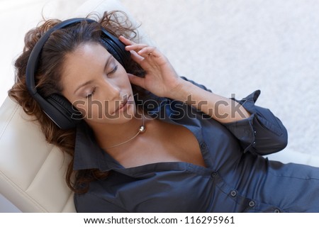 Sexy woman listening to music through headphones, eyes closed, view from above.