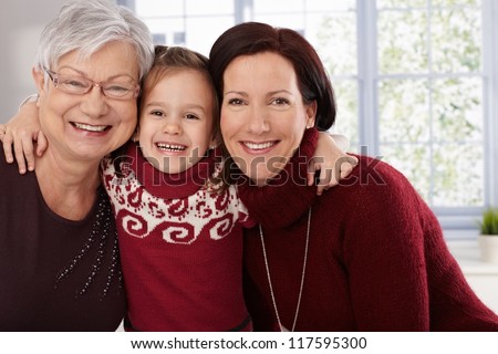 Happy little girl hugging grandmother and mother, all smiling.
