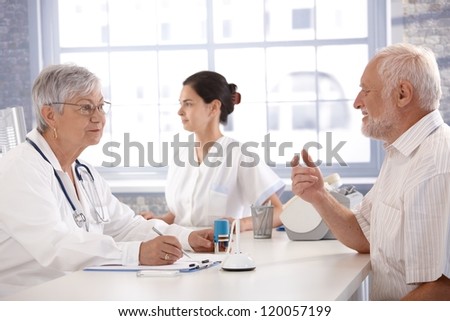 Senior patient sitting at doctor's room, consulting with female doctor.