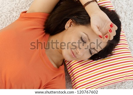 Young girl resting at home on pillow eyes closed.