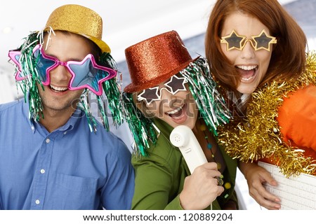 New year celebration in office, office workers in party hat and funny sunglasses having fun.