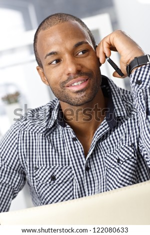Portrait of handsome Afro-American guy speaking on cellphone, smiling.