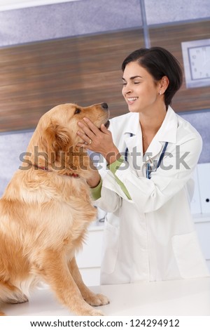Smiling young female veterinary with golden retriever at clinic.
