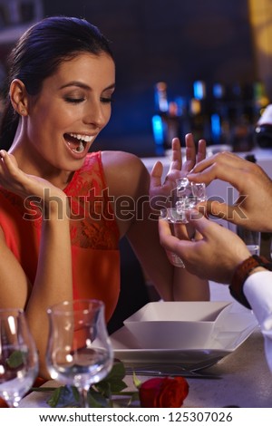 Young woman shouting with hapiness when man handing over engagement ring.