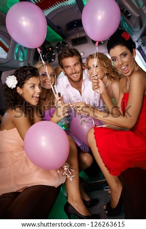 Beautiful young girls having party fun in limousine with handsome man.